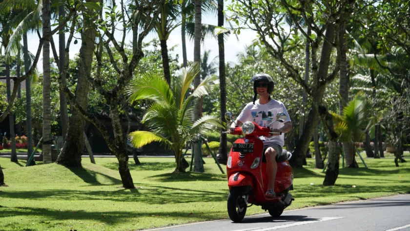 man in white shirt riding red motor scooter on road during daytime
